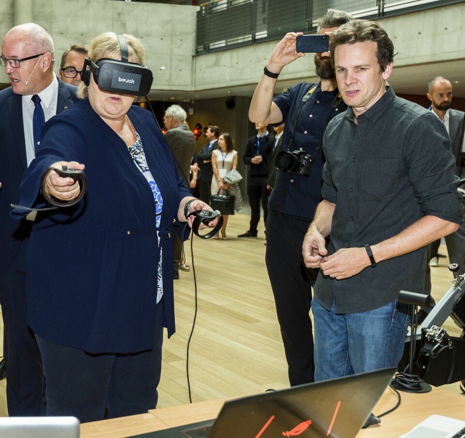 Et regjeringsoppnevnt utvalg ser på hvilke økonomiske virkninger koronakrisen kan få i årene framover, og hvilke veivalg politikerne bør ta. Digitalisering er en av de store omstillingene som kommer i samme periode. Her prøver statsminister Erna Solberg VR-briller i aigist 2018 mens Martin Sivertsen fra Breachvr i Trondheim forklarer. Et regjeringsoppnevnt utvalg ser på hvilke økonomiske virkninger koronakrisen kan få i årene framover, og hvilke veivalg politikerne bør ta. Digitalisering er en av de store omstillingene som kommer i samme periode. Her prøver statsminister Erna Solberg VR-briller i aigist 2018 mens Martin Sivertsen fra Breachvr i Trondheim forklarer.