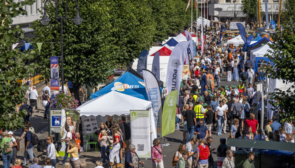 Arendalsuka skal inneholde nær 200 flere arrangement i år i forhold til i fjor. Gate i Arendal med boder fra ulike organisasjoner og etater på rekke og rad. Yrende folkeliv rundt bodene.