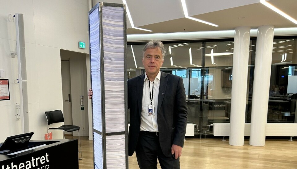 Områdedirektør Helge Eide i KS viser fram bunken med lover og regler som kommunesektoren må forholde seg til.