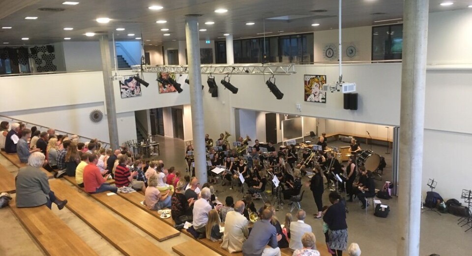 Samtidig som korpset holdt konsert i trappa, foregikk en høylytt håndballkamp rett utenfor. Dørene gikk opp og igjen konstant fordi spillerne kom innenfor fotocelledekningen, skriver Bjørn Riley-Boge.