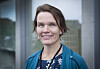 Portrett av Kristin Weidemann Wieland i blå cardigan foran en glassfasade.