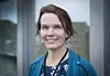 Portrett av Kristin Weidemann Wieland i blå cardigan foran en glassfasade.