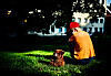 Ung gutt sitter med ryggen til på en solbelyst gressplen i en park.
